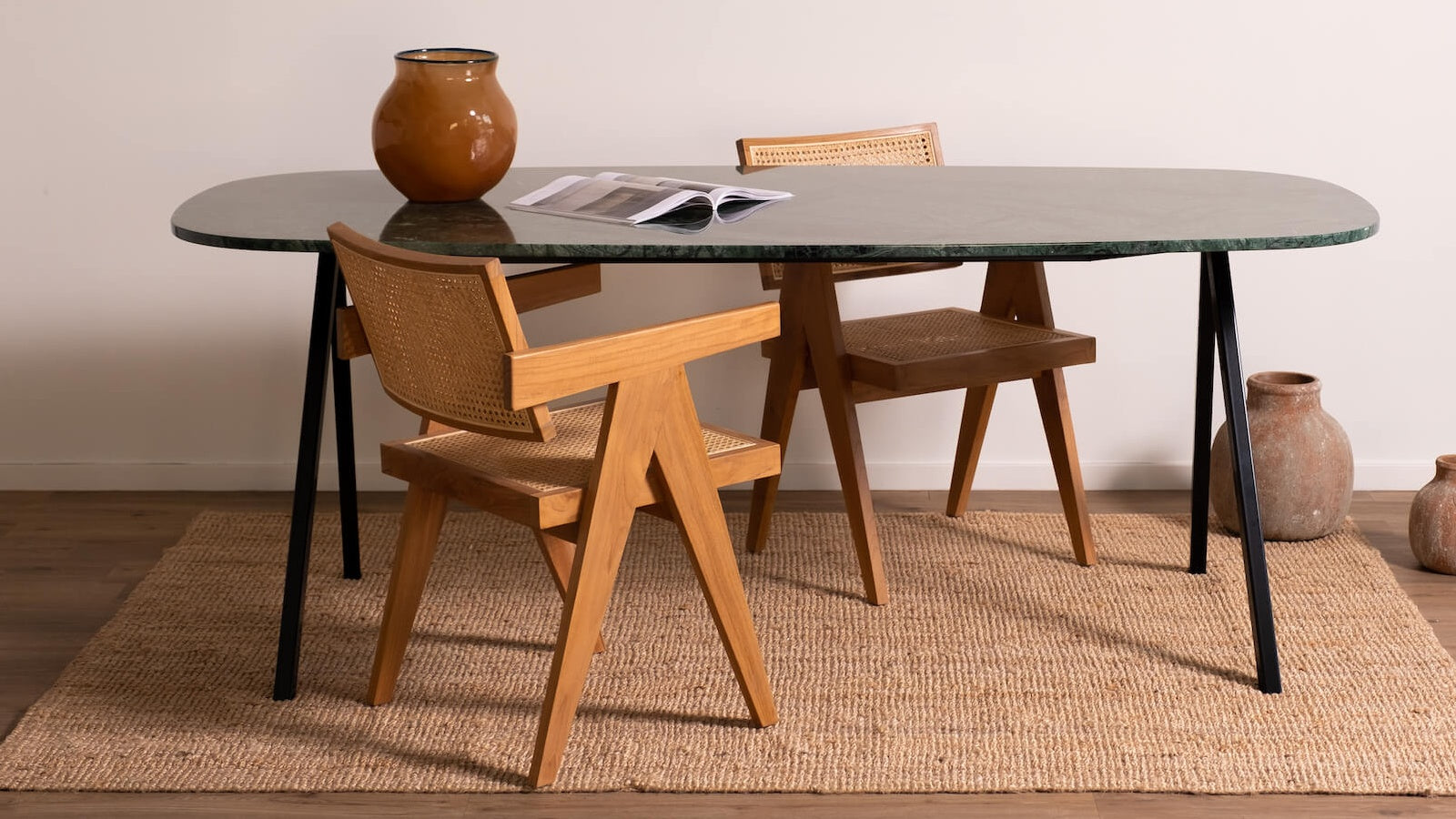 groen marmeren eettafel boot vorm met bruin pierre jeanneret stoelen detail met vaas vooraanzicht