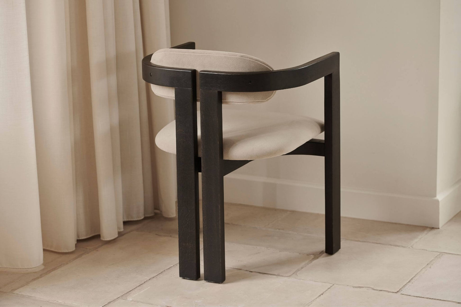 Aide Té Tribute dining chair with black frame and off-white upholstered seat, showcasing modern design and comfortable seating.