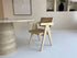 Natural rattan Pierre dining chair by Aime Té featuring a woven rattan seat and curved wooden legs.