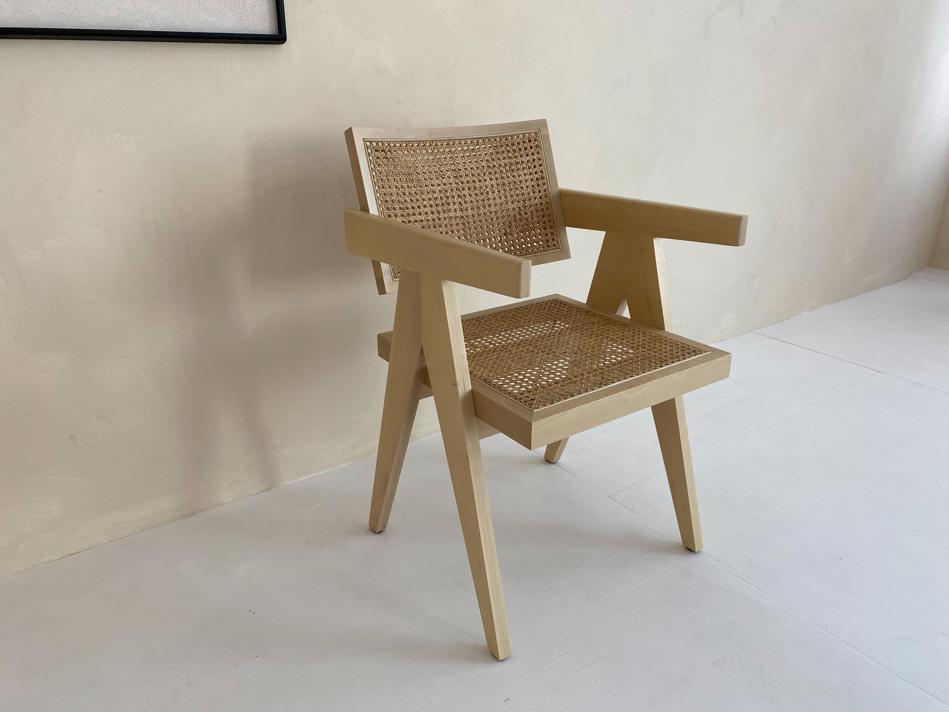 Natural rattan dining chair named Pierre by Aime Té, showcasing woven rattan seat and backrest with a sleek wooden frame.