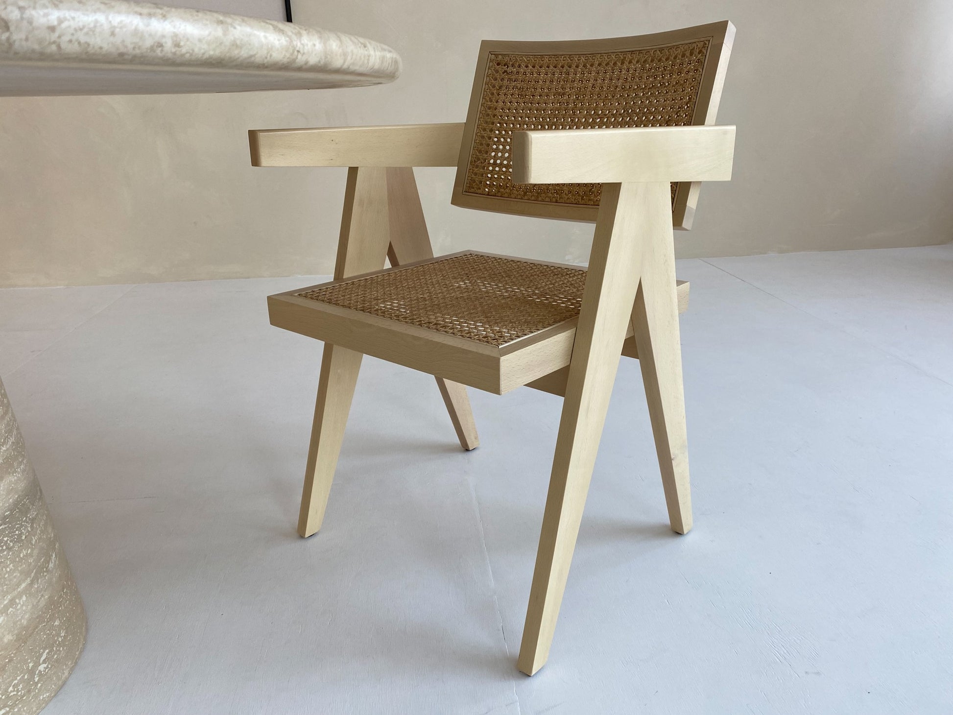 Natural rattan dining chair named Pierre by Aime Té, showcasing woven rattan seat and backrest with wooden legs.
