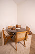 Round marble dining table with dark Emperador brown surface and arch-style metal frame, designed for elegant dining spaces.