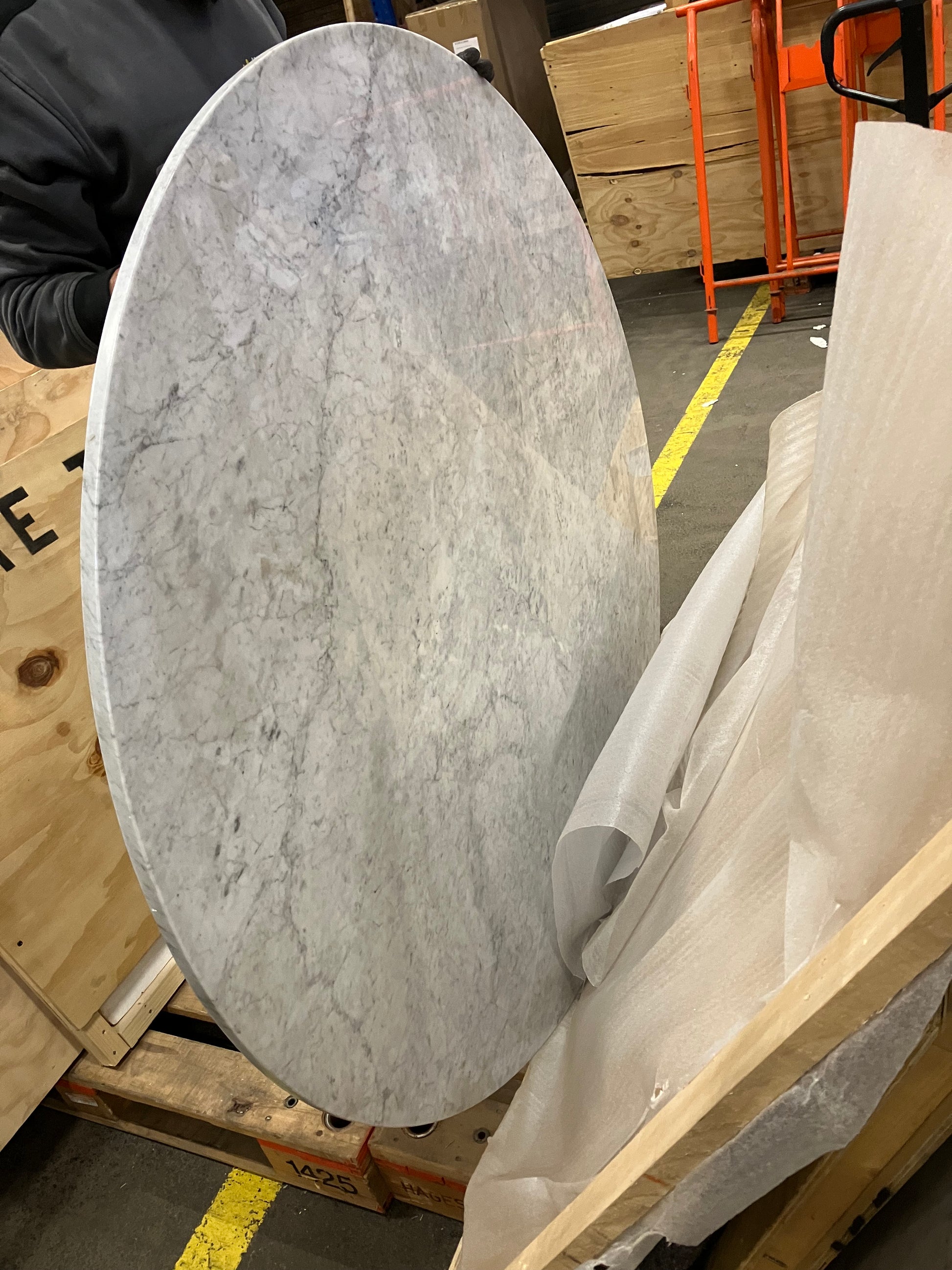 Round KIYO dining table with Bianco Carrara white marble top, showing a small dent and glue residue on the side.