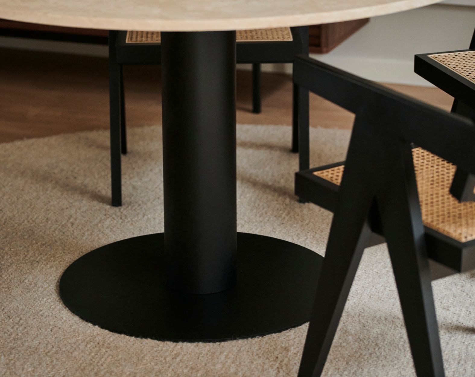 KIYO round dining table with black center leg and travertine surface, slight side damage and small stains visible in the image.