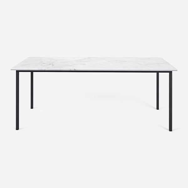 Rectangular marble dining table with four legs in Bianco Carrara white with matte finish and dent detail in the center.