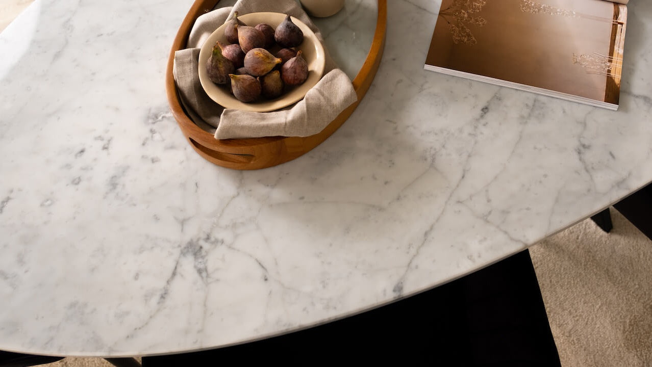 Glossy oval marble dining table with Bianco Carrara white surface and arch-style base, ideal for modern dining rooms.