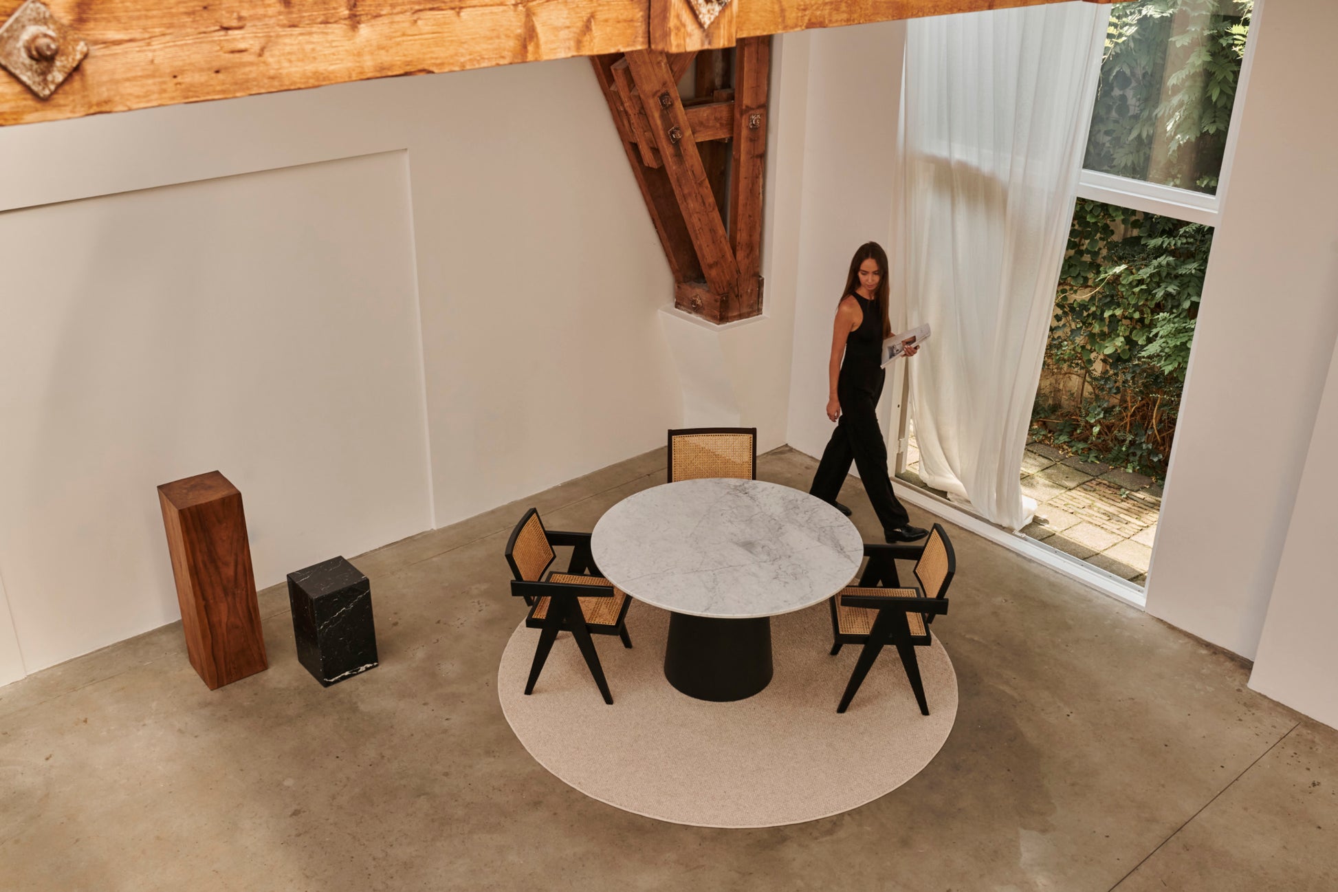 Flow oval dining table with Crema Marfil beige marble top and black cylindrical base, glossy finish, 180x90 cm.