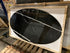 Oval Nero Marquina marble dining table with a cross-frame base, glossy finish, showing stains and scratches, 180x90 cm.
