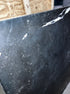 Rectangular Nero Marquina black marble dining table with U-frame, matte finish, showing light scratches and damaged edges.