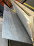 Rectangular marble dining table with white Bianco Carrara marble surface, four legs, glossy finish, minor scratches visible.