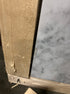 Rectangular marble dining table in Bianco Carrara White with four legs, featuring a matte finish and small chip detail.