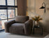 Nollie Monza 07 Earth armchair with plush fabric upholstery and modern design, featuring wooden legs and comfortable seating.