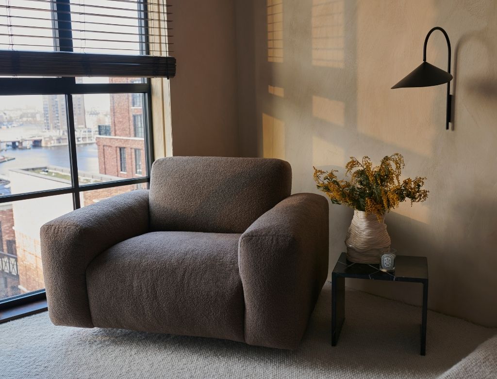 Nollie Monza 07 Earth armchair with plush fabric upholstery and modern design, featuring wooden legs and comfortable seating.