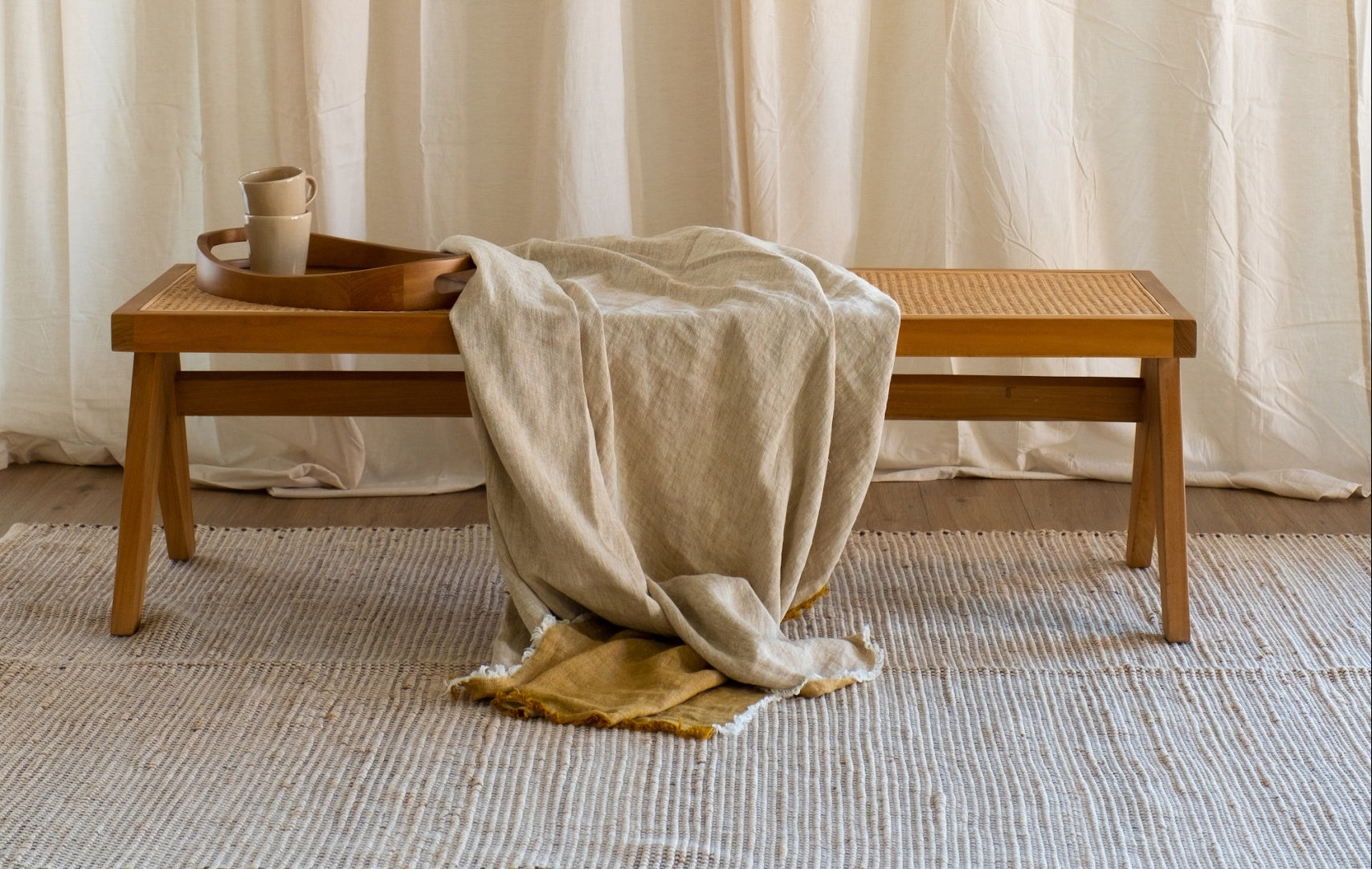 Brown rattan bench named Pierre with a sturdy frame, perfect for indoor or outdoor seating.