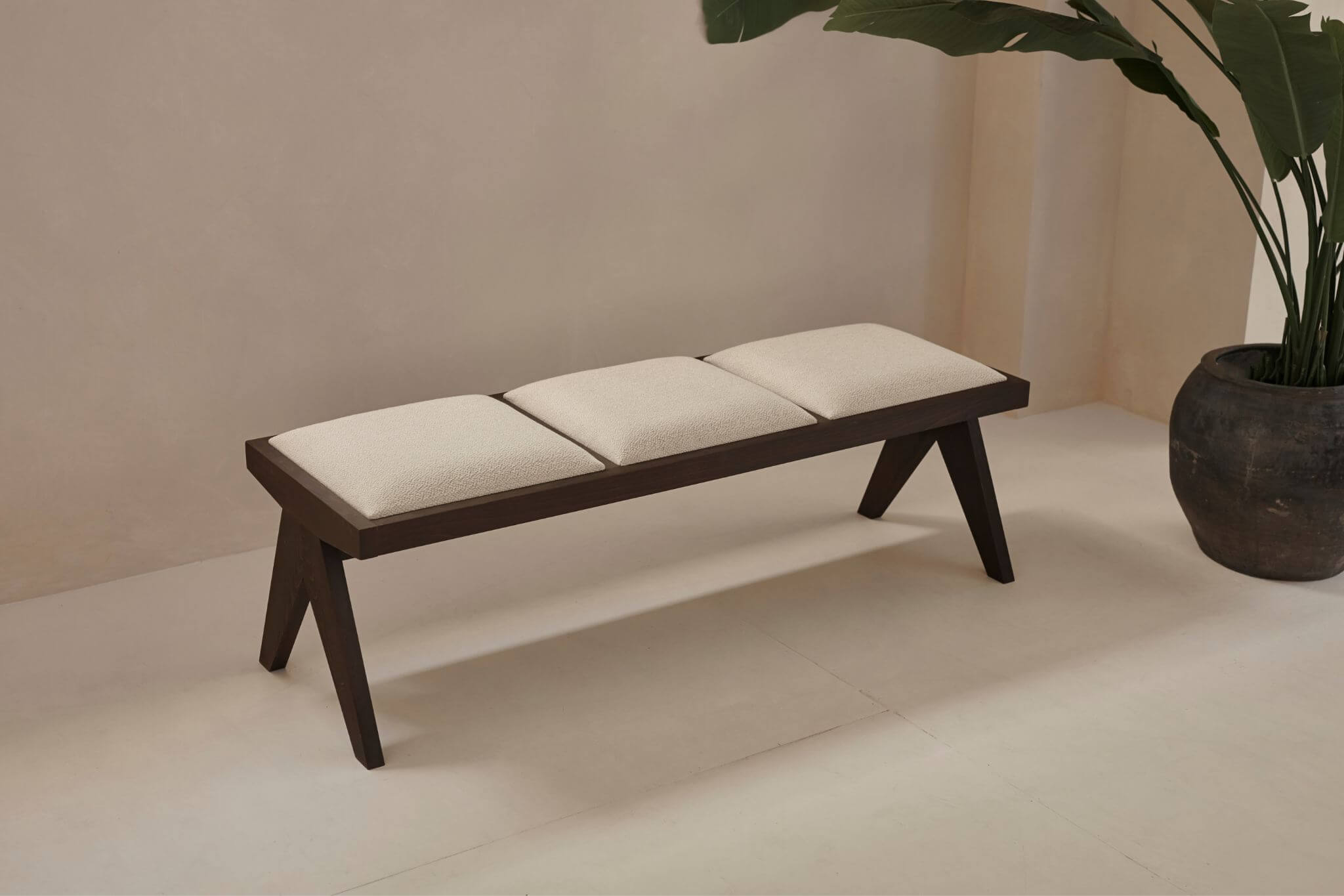 Dark brown rattan bench with upholstered seat named Pierre, stylish and sturdy for indoor or outdoor use.