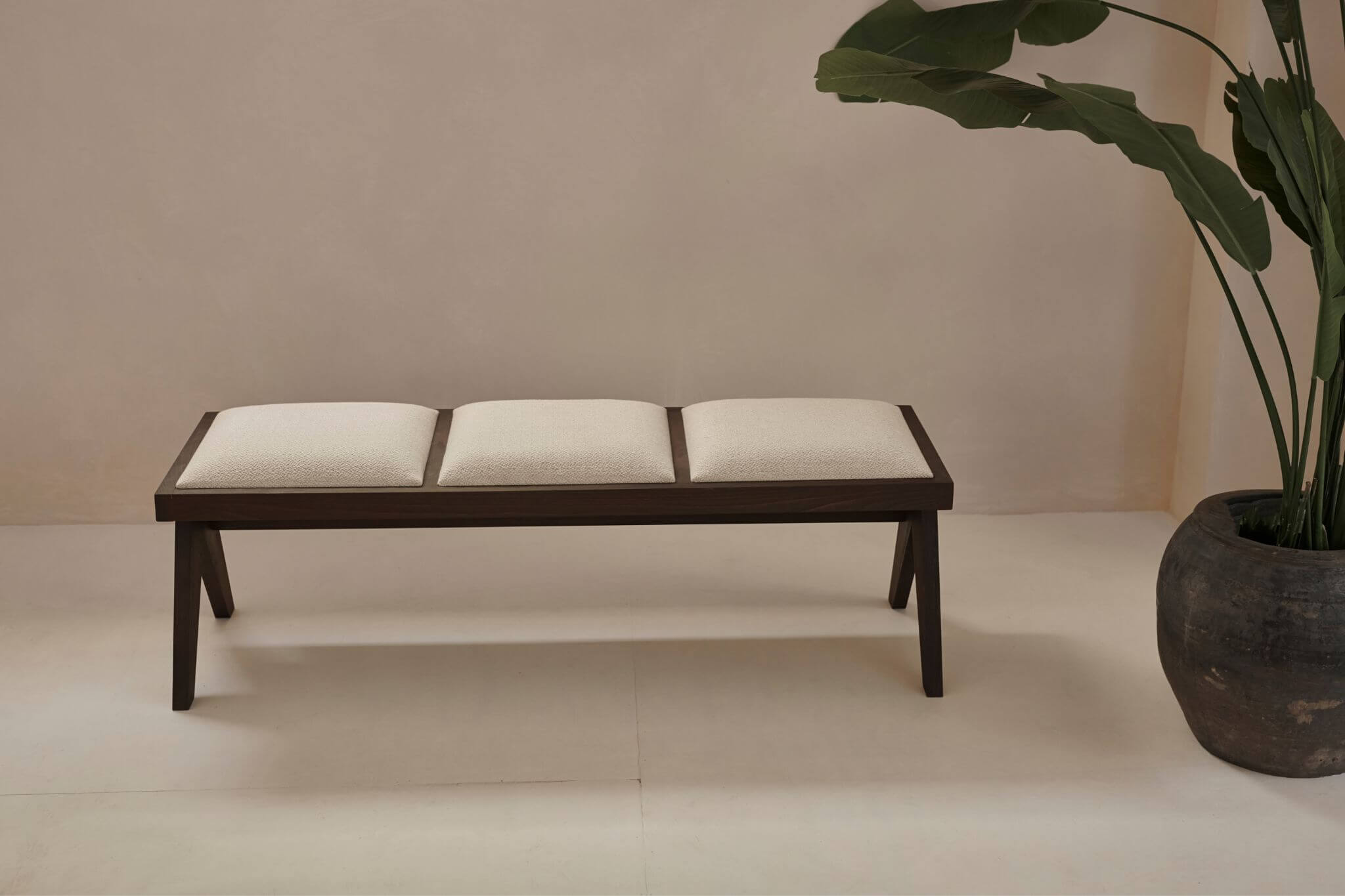 Dark brown rattan bench with upholstered seat named Pierre, featuring a stylish and comfortable design for living spaces.