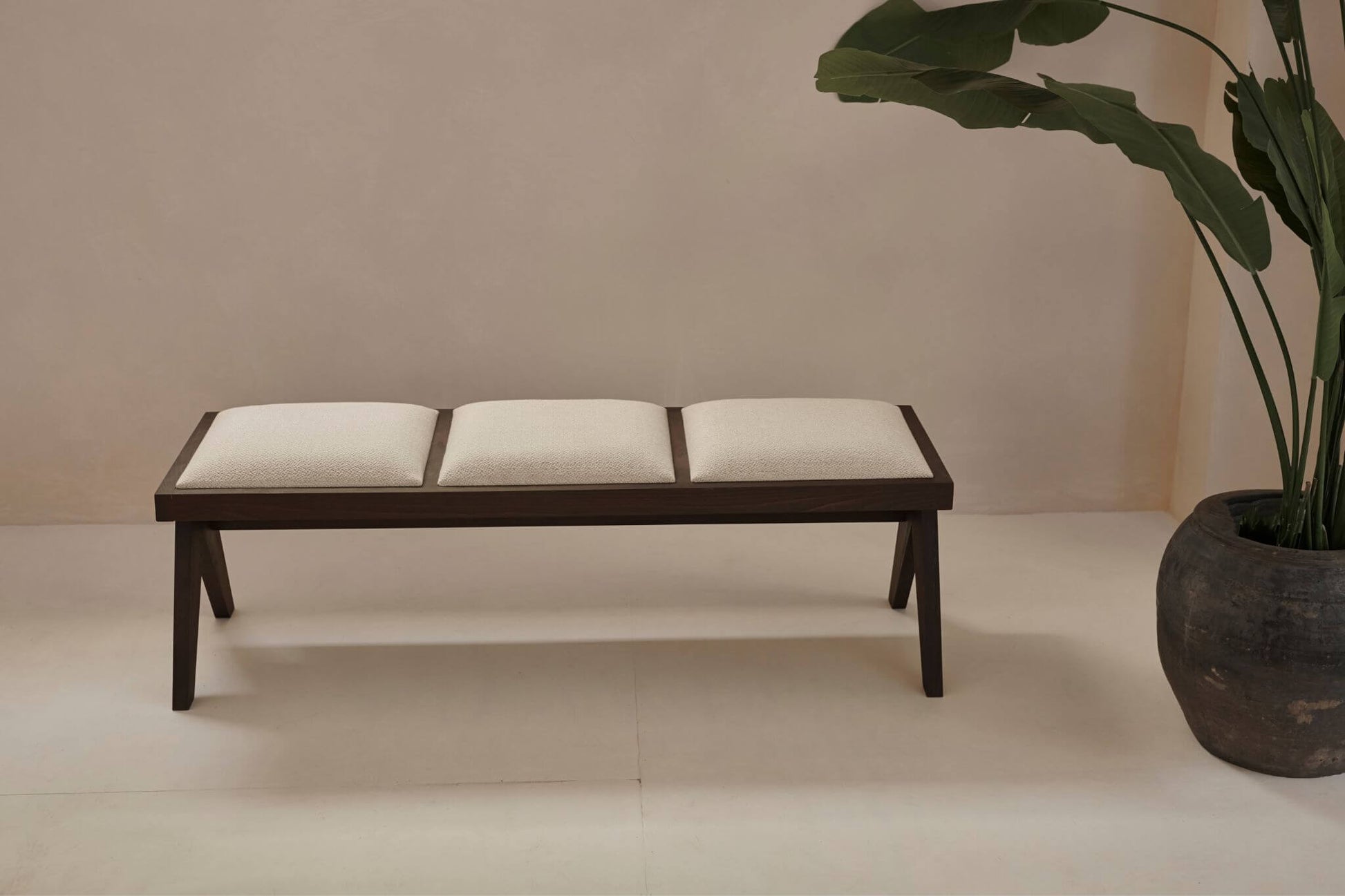 Dark brown rattan bench with upholstered seat named Pierre, featuring a stylish and comfortable design for living spaces.