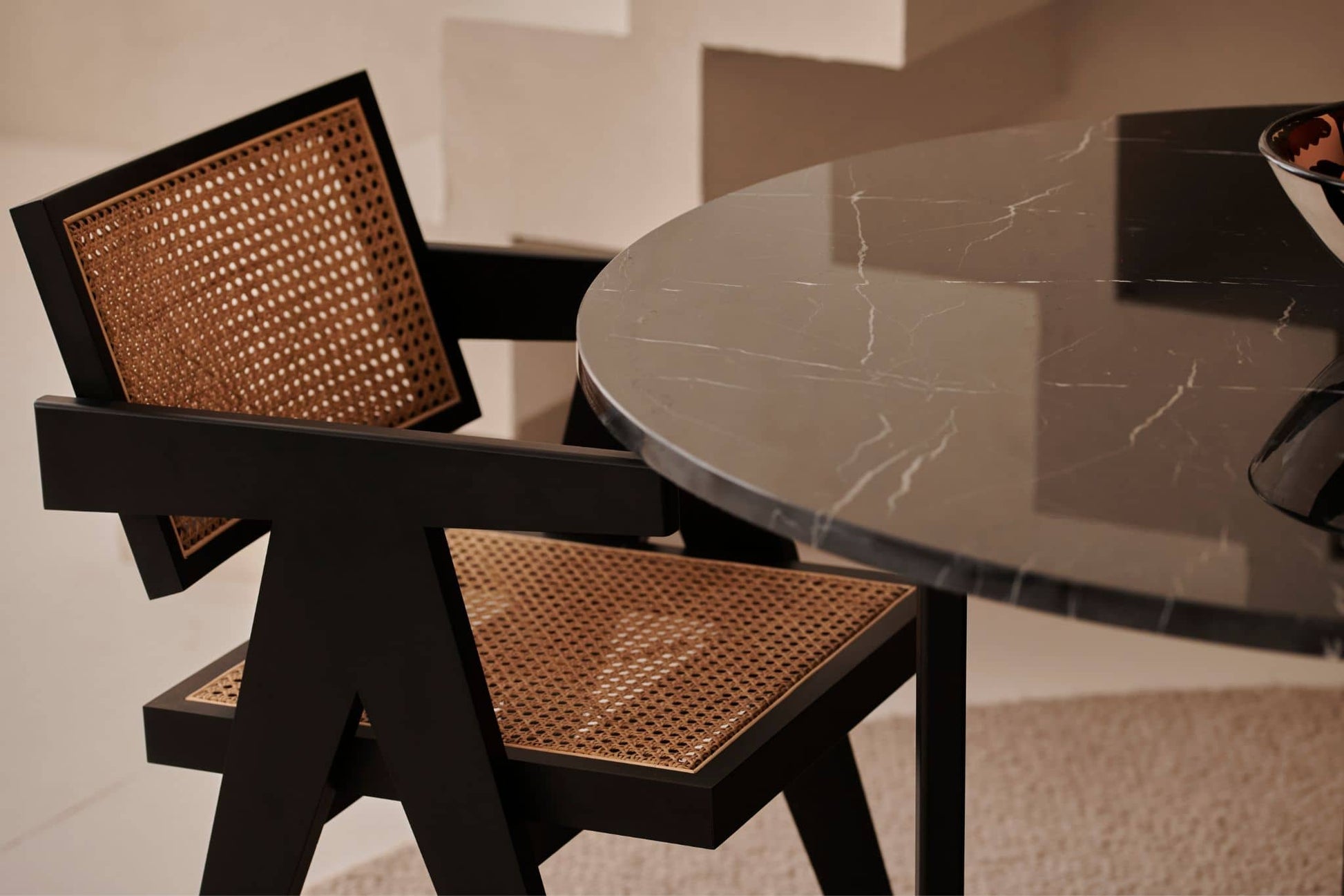 Black rattan dining chair named Pierre with a modern design, featuring a sturdy frame and stylish woven rattan seat and back.