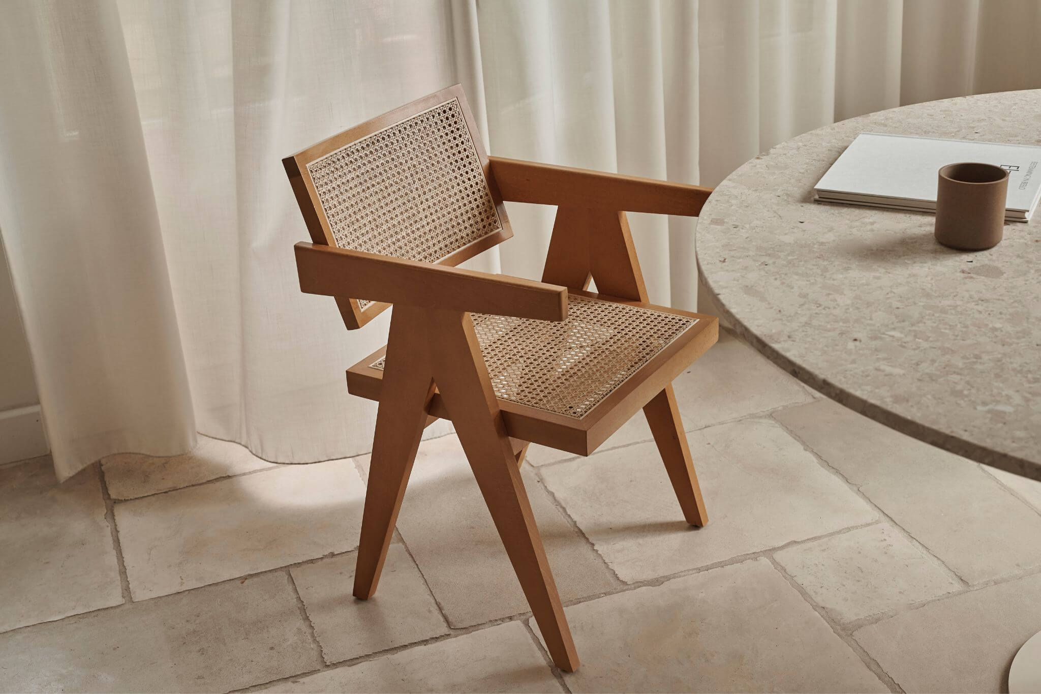 Brown rattan dining chair named Pierre with a natural woven seat and curved armrests, perfect for stylish dining spaces.