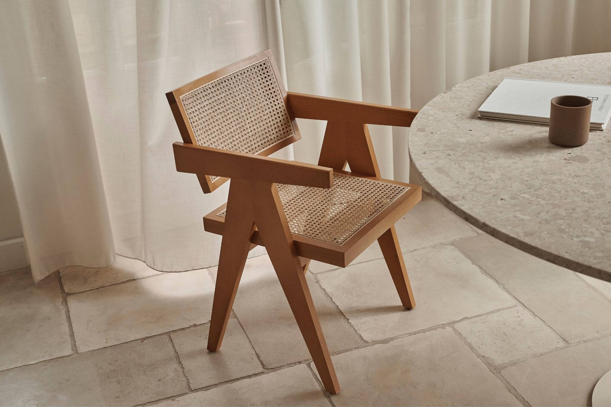 Brown rattan dining chair named Pierre with a natural woven seat and curved armrests, perfect for stylish dining spaces.