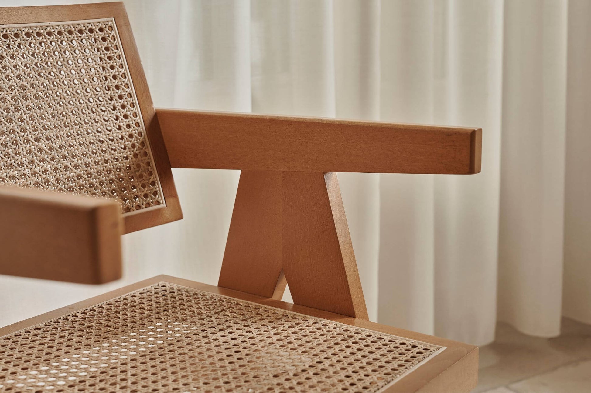 Brown rattan dining chair named Pierre with a sturdy frame and woven rattan seat, perfect for modern dining spaces.