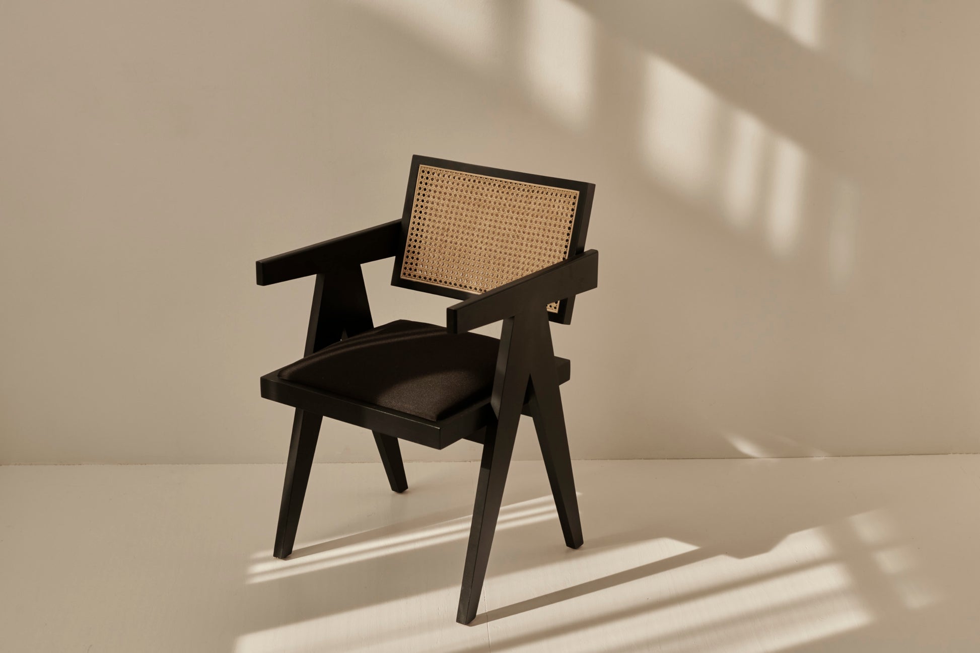Black rattan dining chair with upholstered seat and Pierre design, showcasing a modern and stylish seating option.