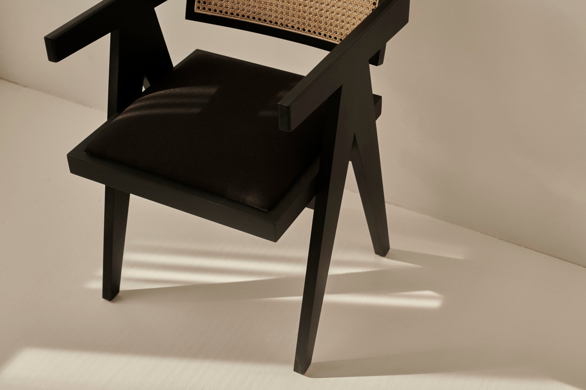 Black rattan dining chair with upholstered seat, stylish Pierre design, featuring a modern and comfortable look for dining spaces.