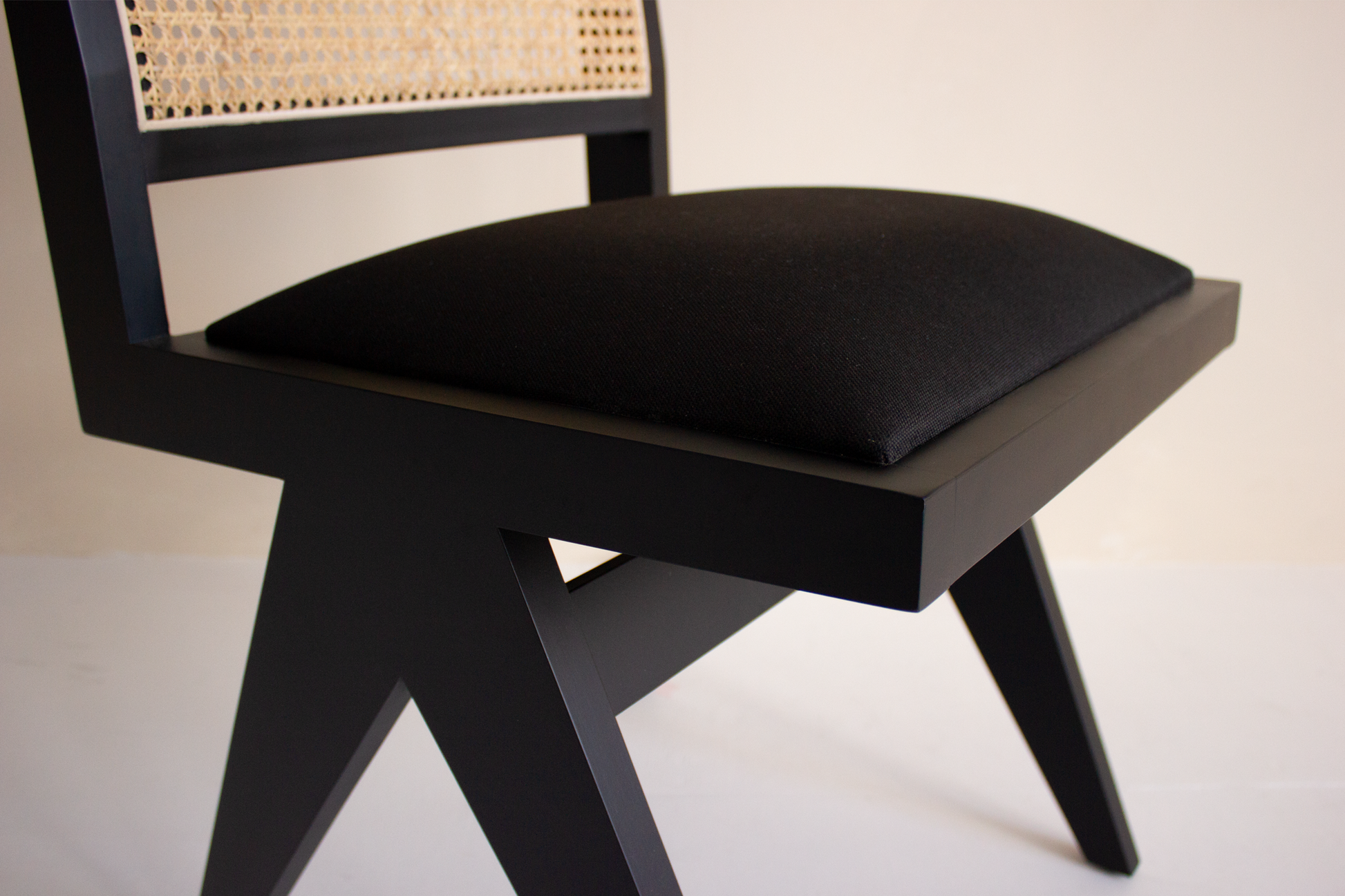 Black rattan dining chair with upholstered seat and no armrests, featuring a modern design by Pierre.