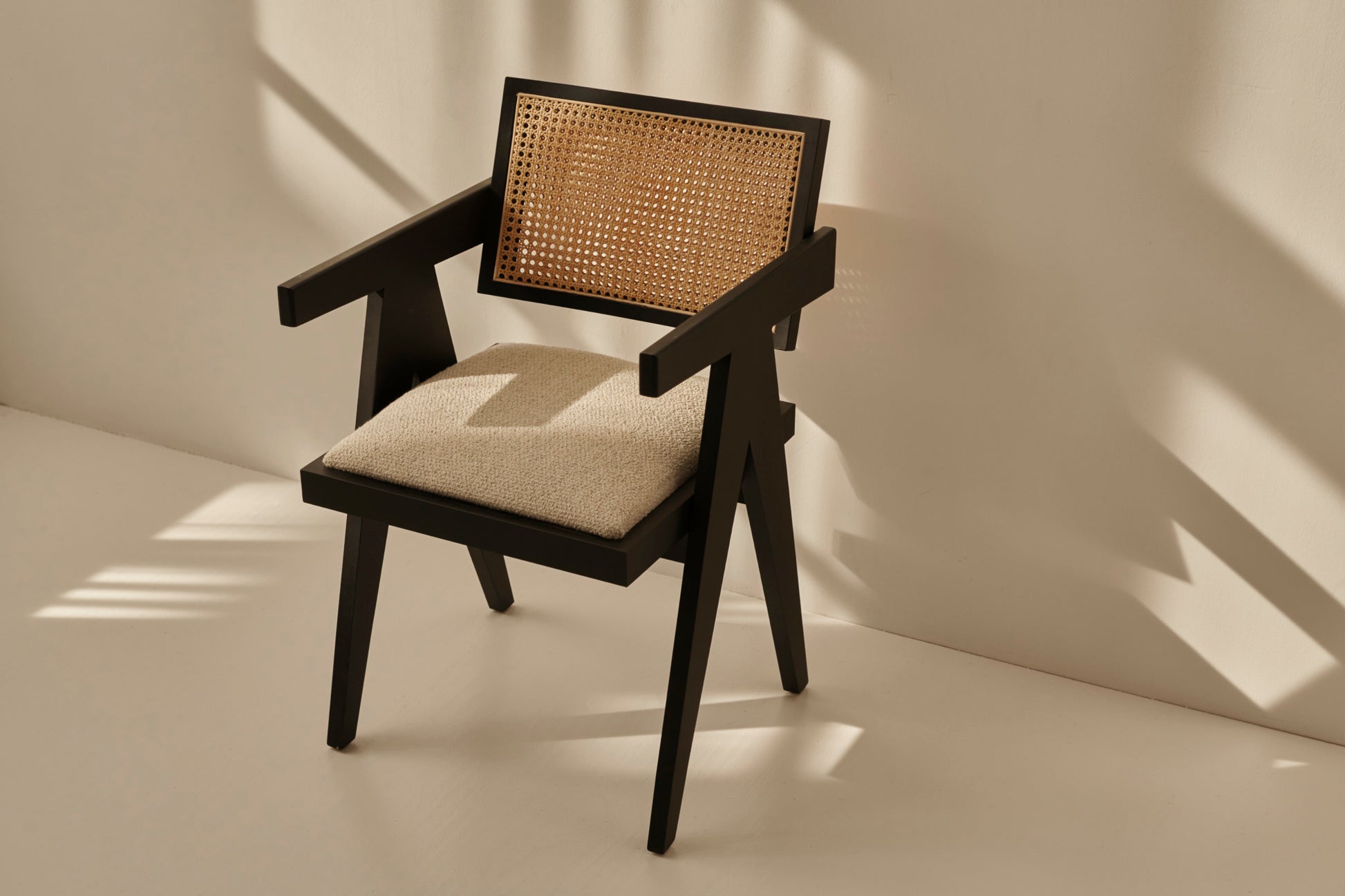 Black rattan dining chair with upholstered seat named Pierre, showcasing a stylish and comfortable design for modern dining spaces.