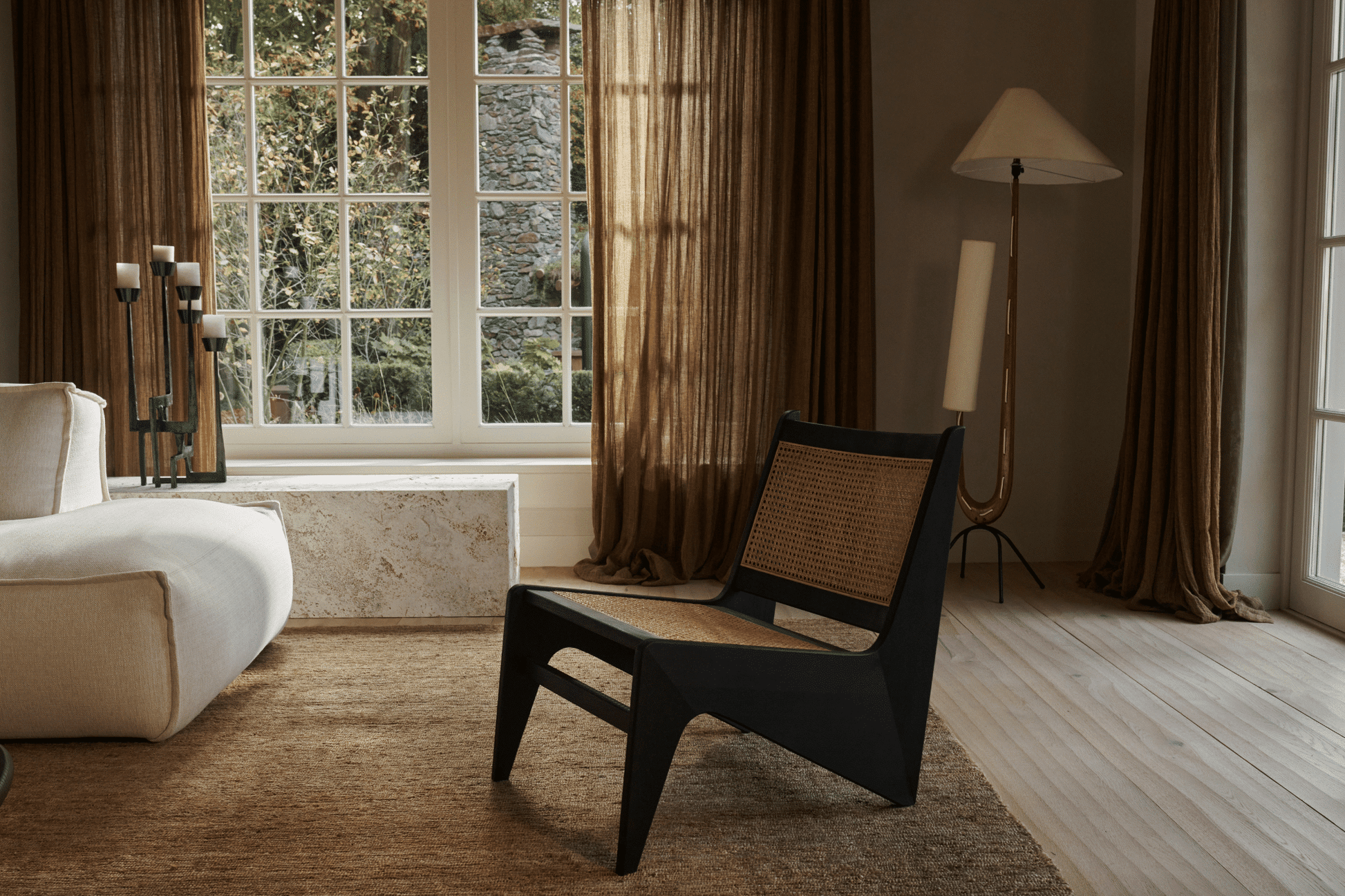 Brown rattan Kangaroo Chair named Pierre with a curved design, perfect for stylish, comfortable seating in modern interiors.