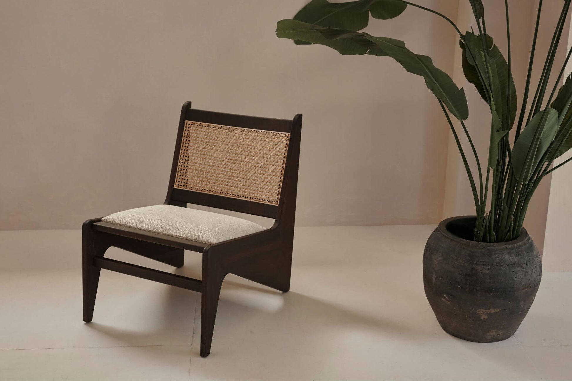 Dark brown rattan Kangaroo Chair with upholstered seat named Pierre, featuring a stylish, cozy design for living room decor.