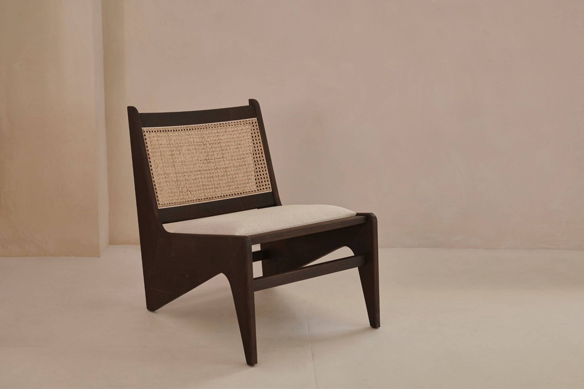 Dark brown rattan kangaroo chair with upholstered seat in the Pierre style, featuring a cozy and stylish design.
