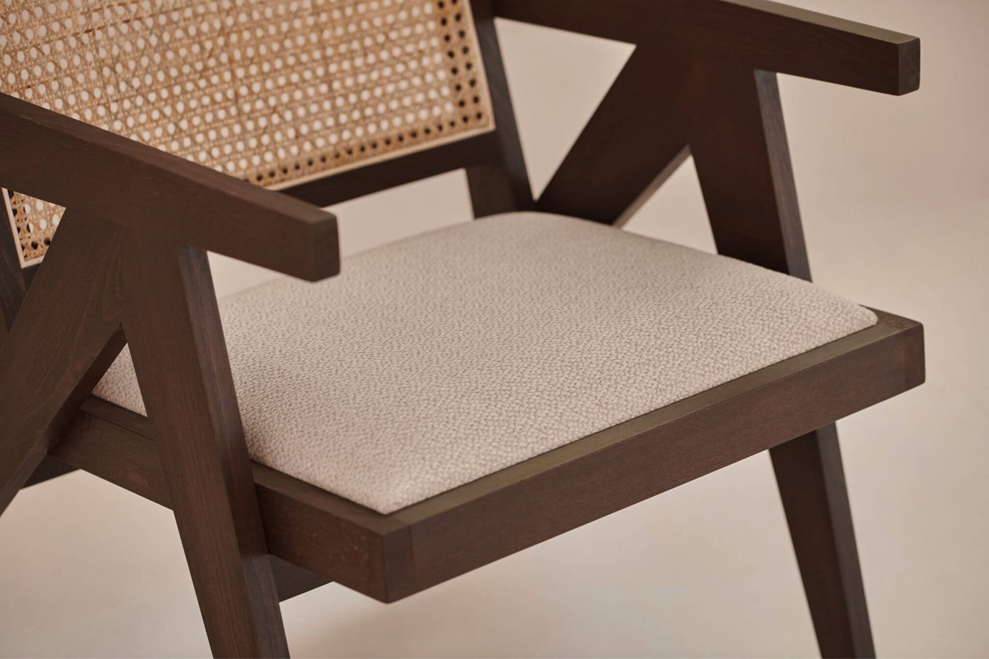 Dark brown rattan lounge chair with upholstered seat, modern Pierre design for comfortable outdoor or indoor relaxation.