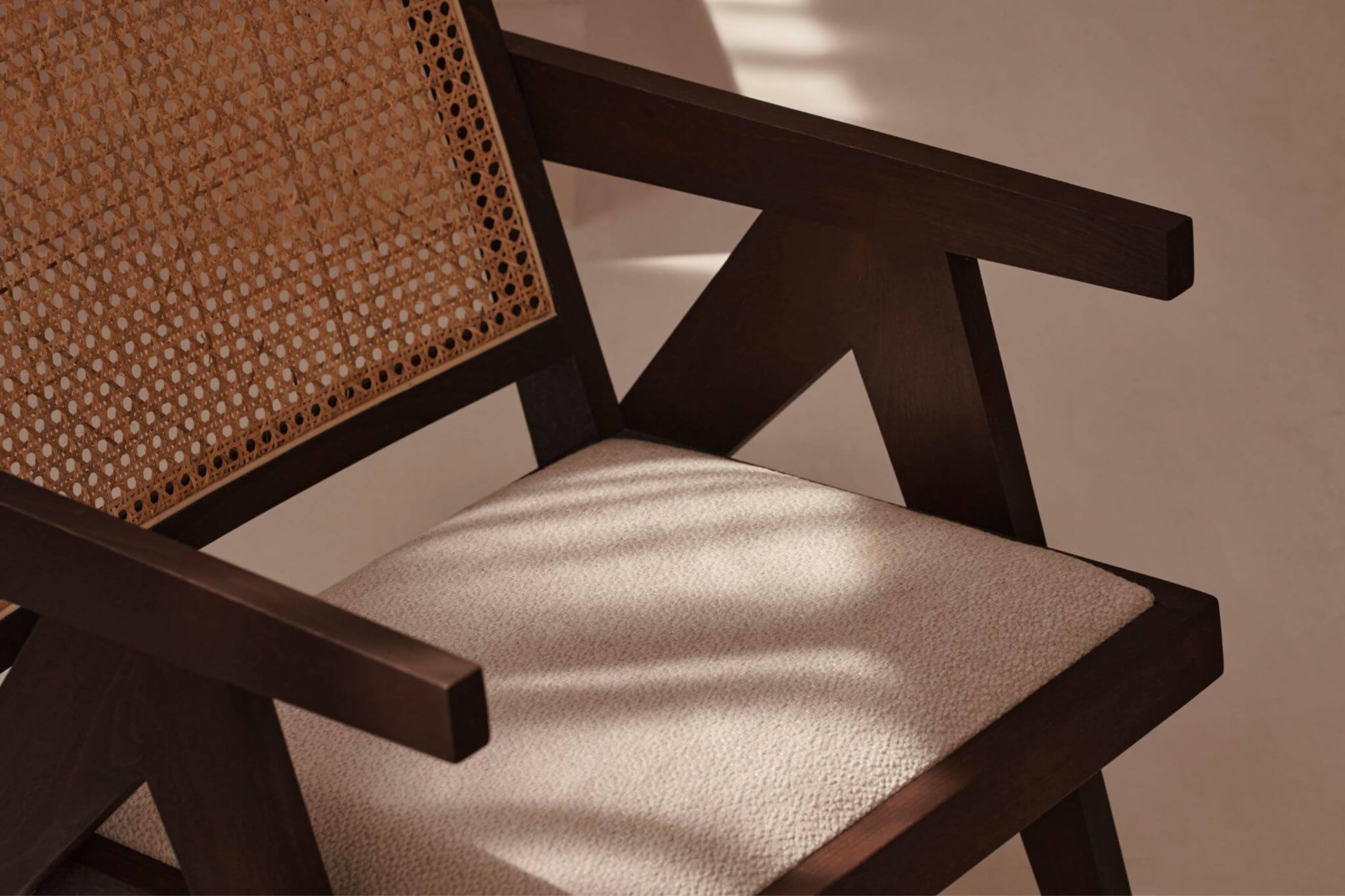 Dark brown rattan lounge chair with upholstered seat named Pierre, stylish and comfortable for indoor or outdoor relaxation.