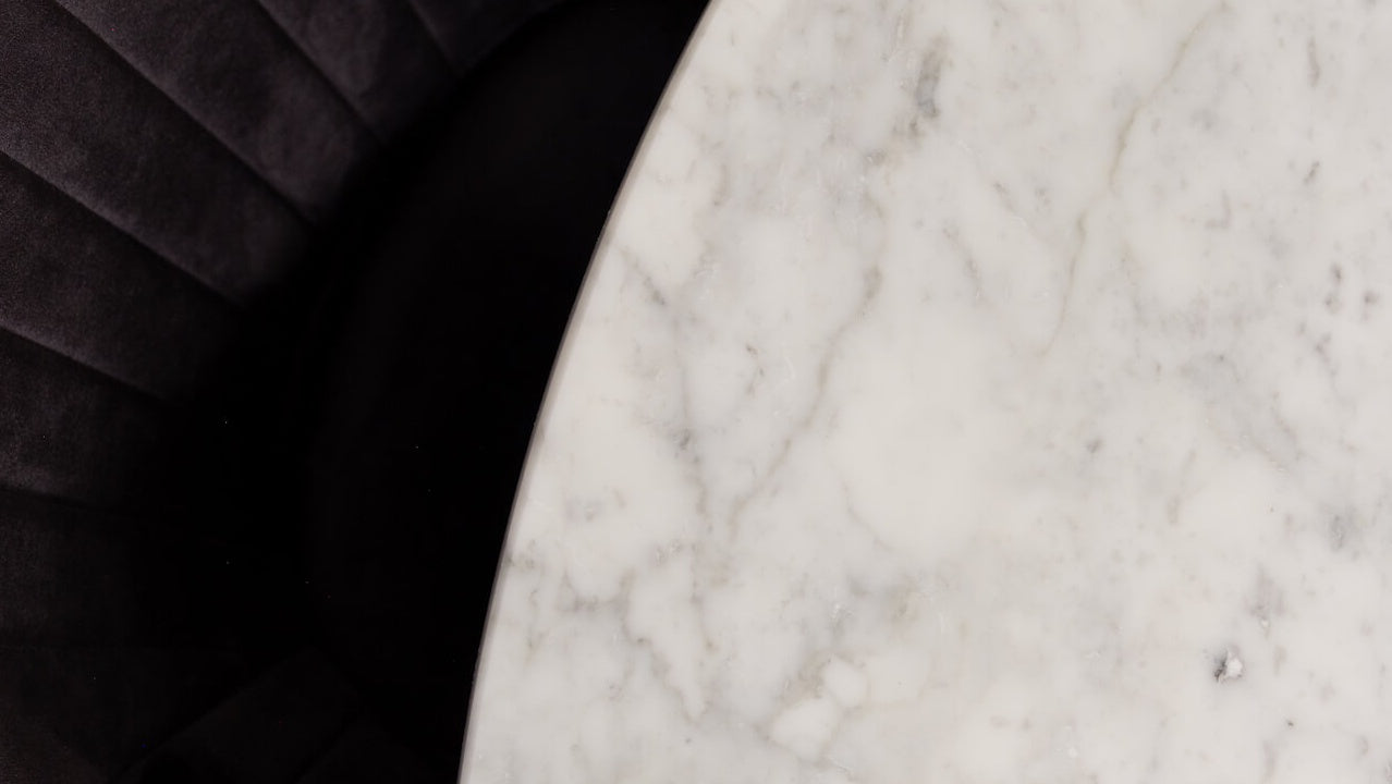 Round marble dining table with Bianco Carrara white surface and arch metal frame, sleek and glossy for modern dining rooms.