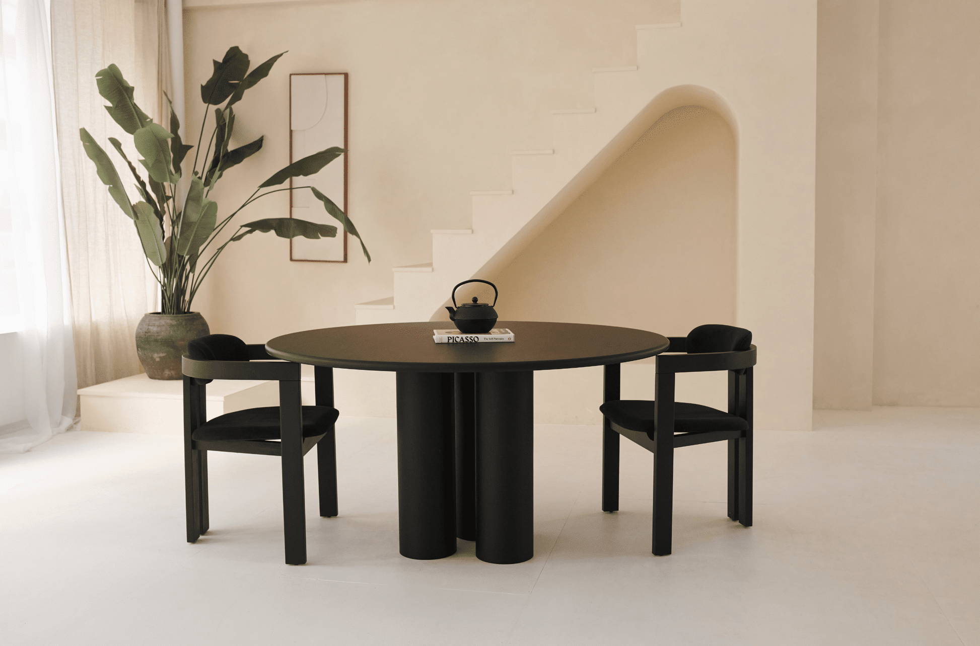 Black oak round dining table named FRANKY with a sleek design, featuring a sturdy base and smooth tabletop surface.