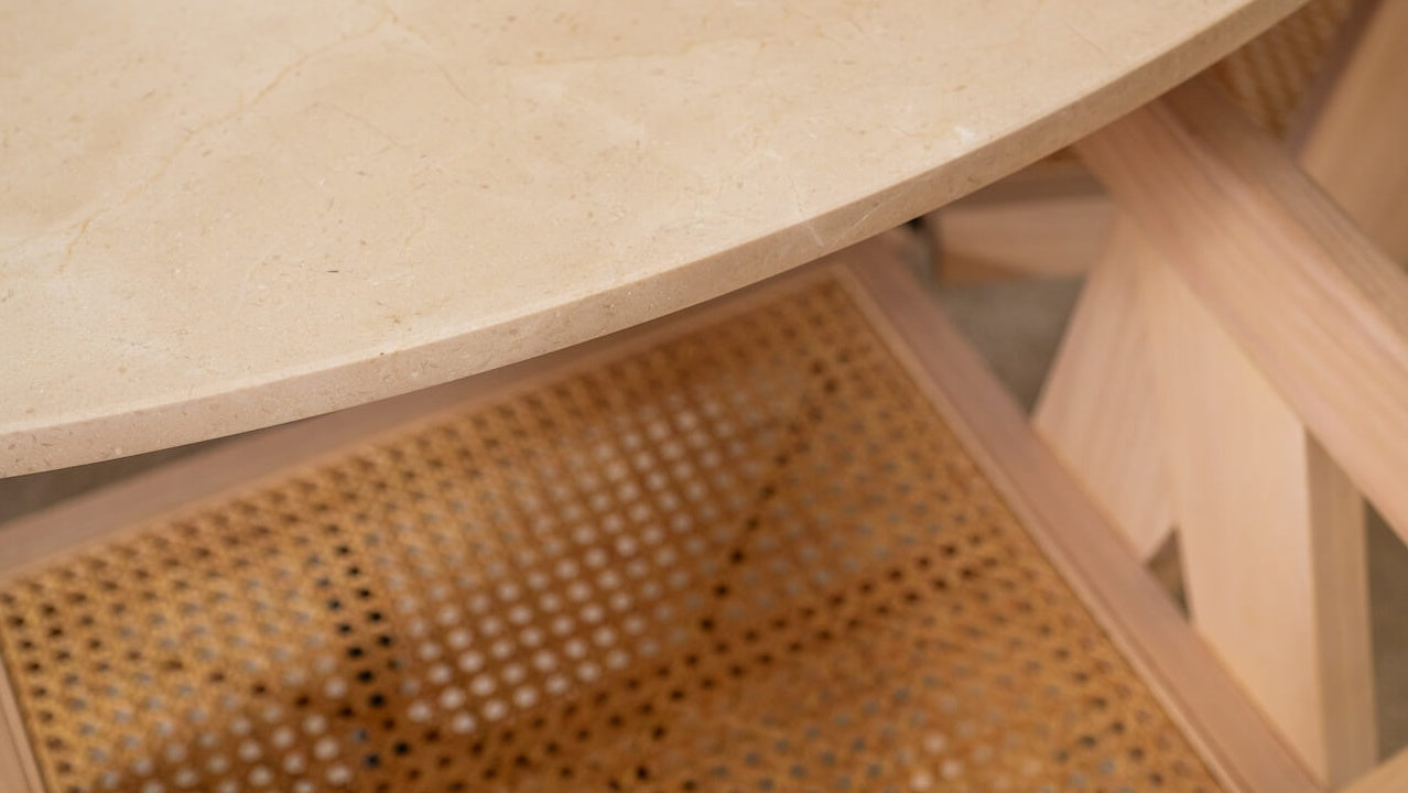Round KIYO dining table with Crema Marfil beige marble top and black center-leg, matte finish with subtle dents on the sides.