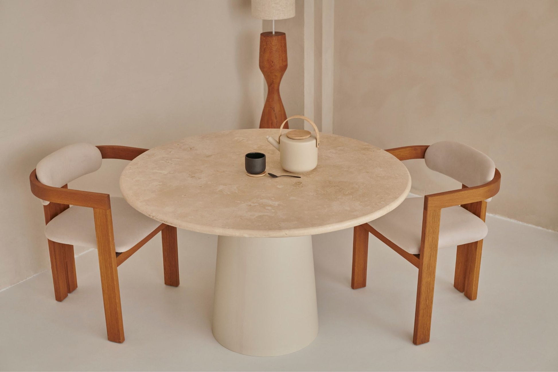 Flow round dining table with black travertine top and cylindrical base, stylish modern design for contemporary dining spaces.