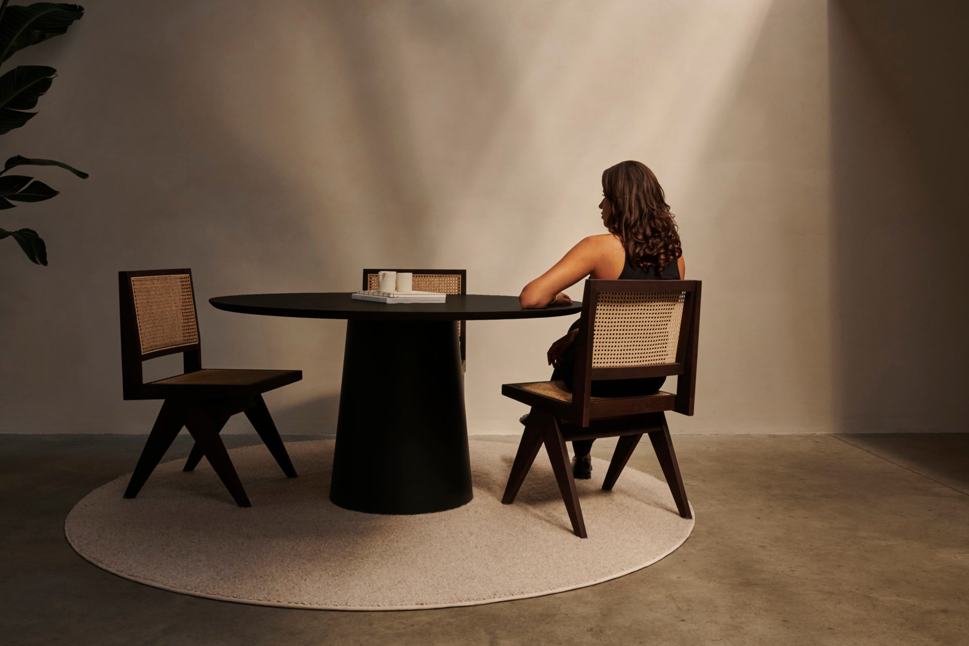 Flow round dining table with smoked oak tabletop and black cylindrical base, modern design for contemporary dining spaces.