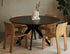 Round oak dining table with charcoal finish and arched frame, showcasing smooth wooden surface and sturdy design.