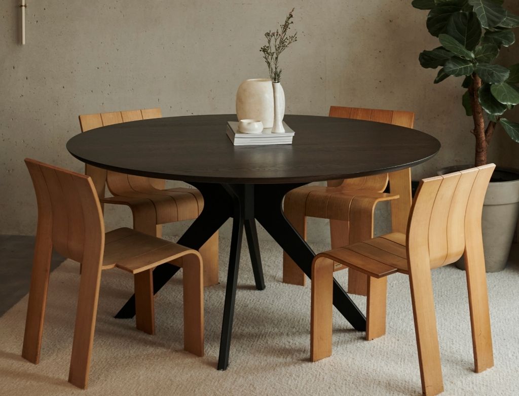 Round oak dining table with charcoal finish and arched frame, showcasing smooth wooden surface and sturdy design.