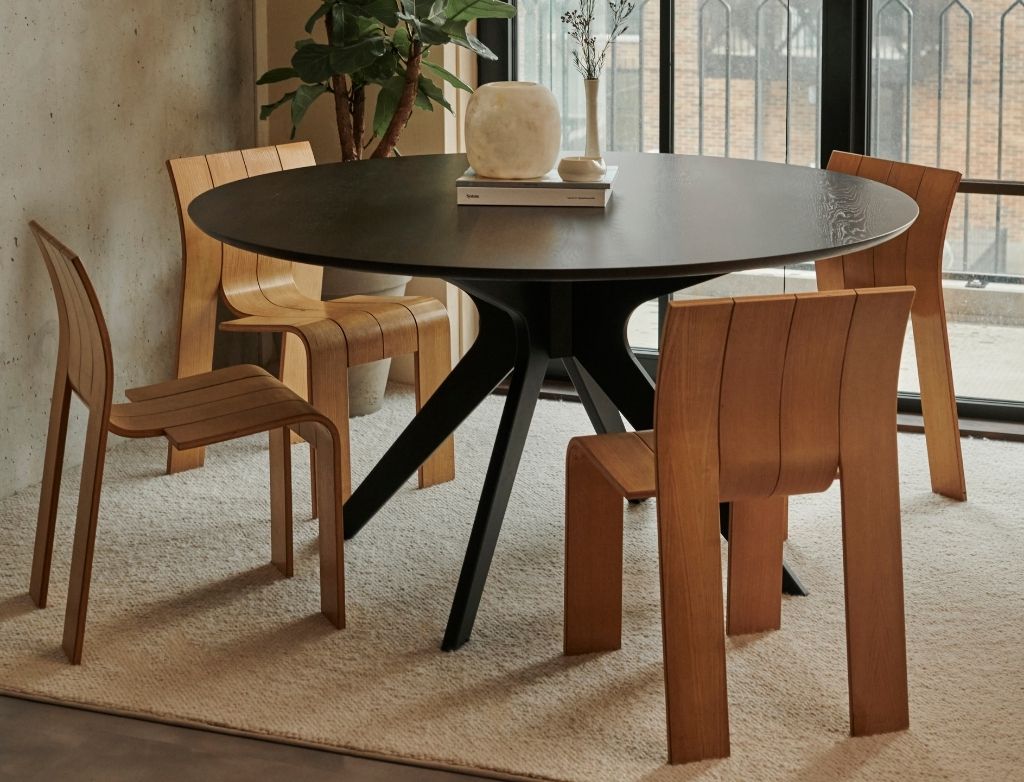Round oak dining table with charcoal finish and arched frame, perfect for modern dining rooms.