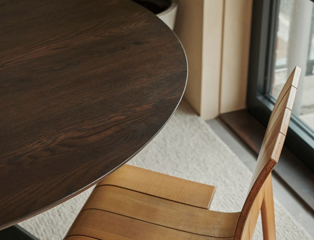 Round oak dining table with arched charcoal frame, showcasing a sleek, modern design perfect for contemporary dining spaces.