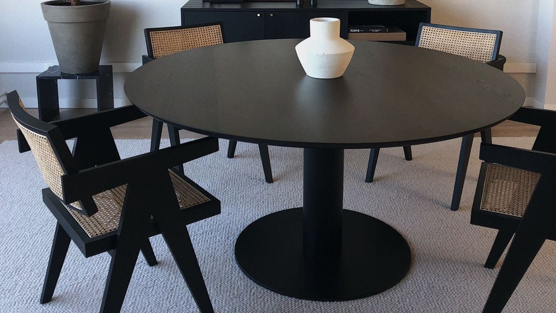 Round oak dining table in charcoal with a center leg design, showcasing a sturdy and stylish wood dining piece.