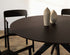 Round walnut dining table with an arched frame, showcasing a sleek wooden surface and elegant curved legs.