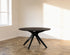 Round walnut dining table with arched frame, showcasing a sleek, modern design and smooth wooden surface.
