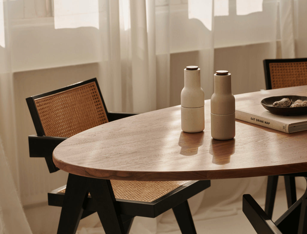 Oval walnut dining table with arched frame, showcasing smooth wood finish and modern design for elegant dining spaces.