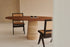Oval walnut FLOW dining table with travertine cylinder base, 180x90 cm, modern and elegant design.