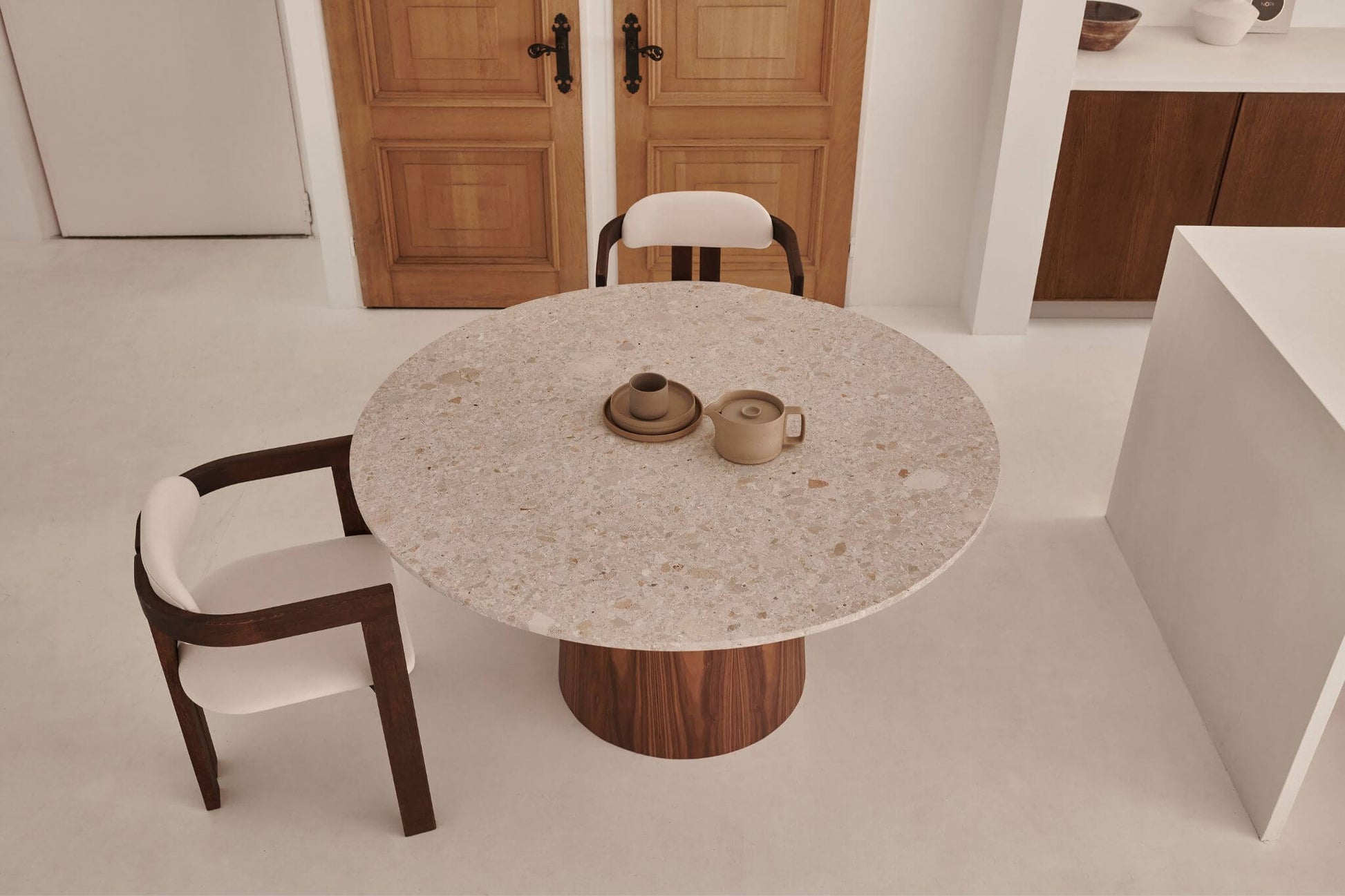 Round dining table with Crema Altea marble top and black cylinder base, sleek and modern design by My Store.